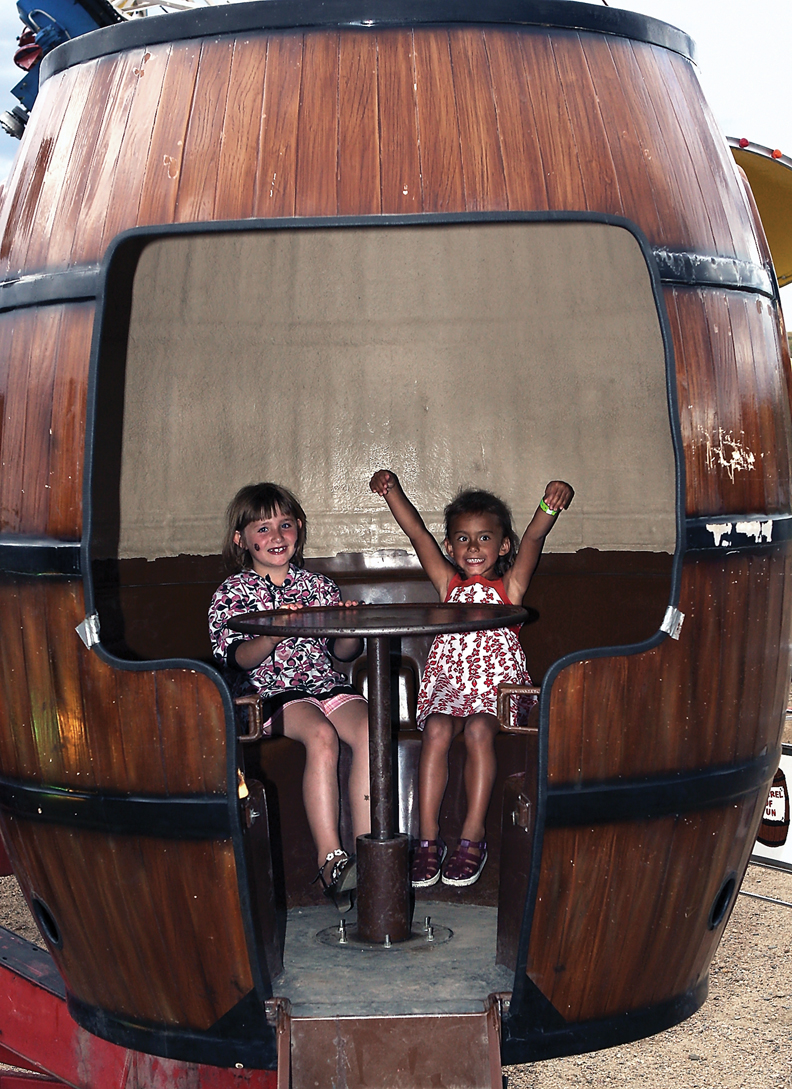 Naleah Lloyd, 7, left, and Hailey Collins, 5, get ready for the “Barrel of Fun” ride Saturday at the Moffat County Fairgrounds.