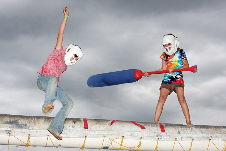 Genevieve Krause, 9, heads toward the padded pit after getting knocked off the plank by Amanda Moore, 9, at the carnival Saturday at the Moffat County Fairgrounds. The FACEoff attraction was one of the most popular at the event after the Gravitron broke down.
