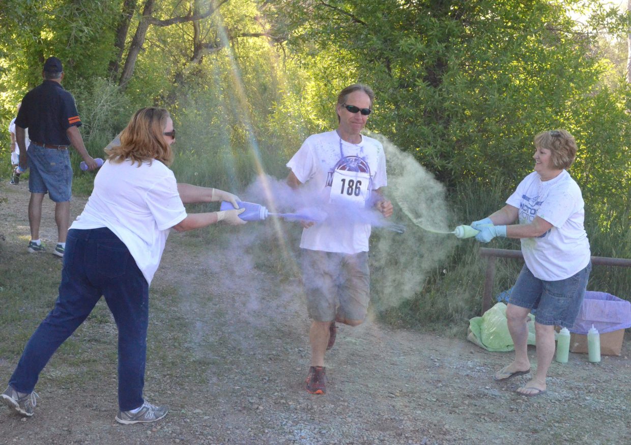 Volunteers cover runner Derek Cleverly with color as he exits the Nature Trail Saturday at Loudy-Simpson Park during the 5K Color Run/Walk as part of the Victory Motors Cancer Drive.