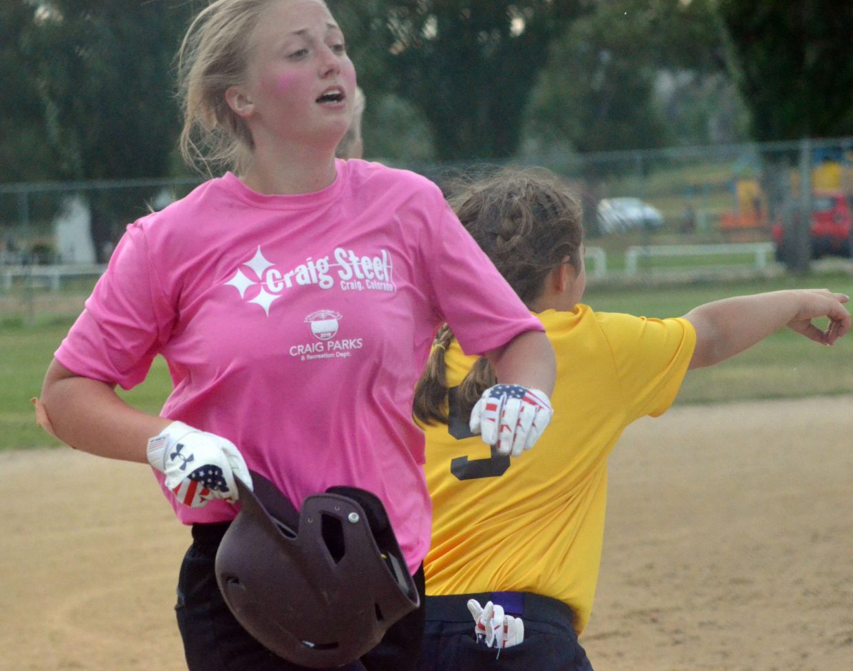 Craig Steel's Justice McMillan rips off her batting helmet as she crosses home plate.