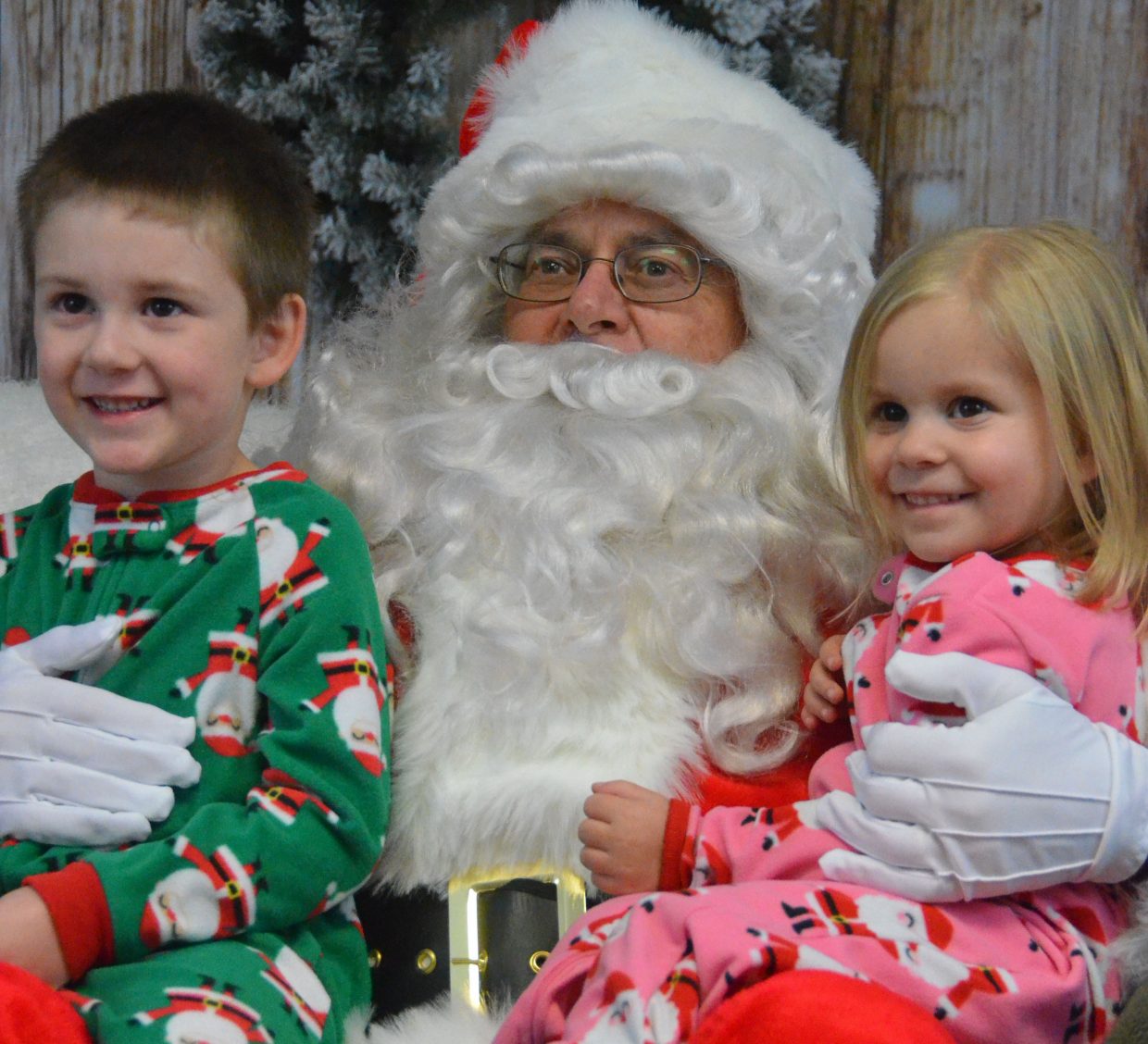 Siblings Rylan, 4, and Xia Hedman, 3, smile for the camera in their holiday pajamas along with jolly old St. Nick during Letters to Santa Tuesday at Justin Stokes State Farm Insurance. 