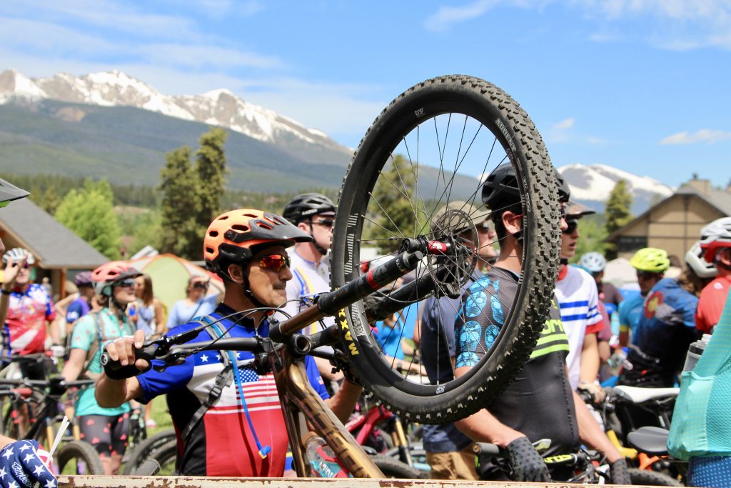 A mountain biker taking part in the Firecracker 50 holds his front wheel in the air.