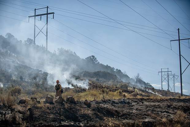 A firefighter walks near damaged power poles in the Lake Christine Fire in July 2018. Holy Cross Energy has taken several steps to increase resiliancy of its system and reduce the risk of the system starting a wildfire.