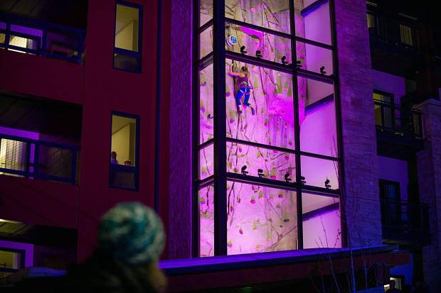 A rock climber ascends the wall on the Limelight Hotel in Snowmass on Saturday night.