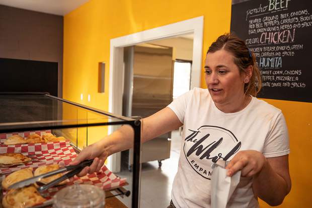 Yanina Dobarro grabs a couple of empanadas from her display case.