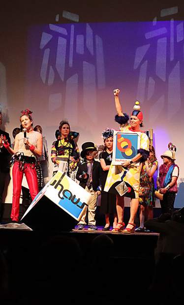 Rachel Hadley Brennaman, in red pants, presents a framed Bauhaus 100 print to Lissa Ballinger for her work on the anniversary extravaganza.
