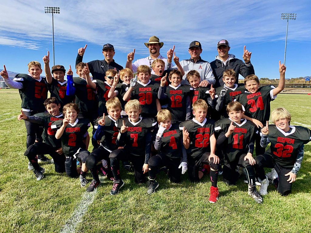 The third- and fourth-grade Aspen football team celebrates after going undefeated (6-0) and winning the championship. The team's starting defense did not allow a single point scored.