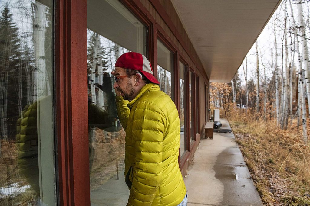 Eric Kaika peeks through the window of the main lodge on the property of the Aspen Camp of the Deaf and Hard of Hearing on Thursday, Nov. 21, 2019. (Kelsey Brunner/The Aspen Times)