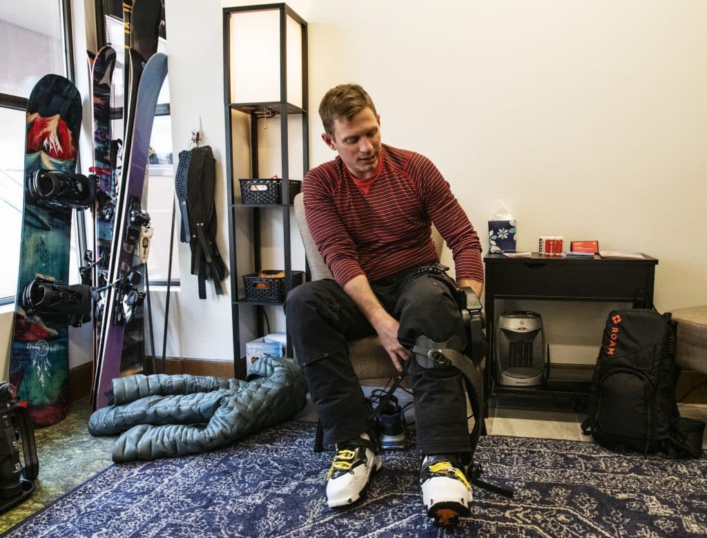 Jim Harris puts on the left leg to the ROAM Robotics Elevate exoskeleton on Friday, Jan. 31, 2020. Harris said that he noticed a huge difference with his skiing once he turned the exoskeleton off. “I really appreciate this, because maybe I’ll feel a little faster and aligned with my own ability,” Harris said of the exoskeleton. (Kelsey Brunner/The Aspen Times)
