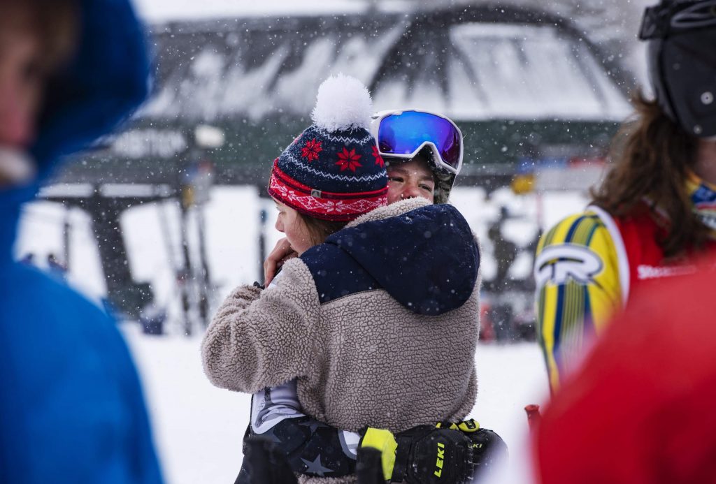 Evelyn Leibinger, left, hugs teammate Jake Morgan after he fell during his first run of the Aspen High School giant slalom at Aspen Highlands on Thursday, Feb. 6, 2020. (Kelsey Brunner/The Aspen Times)
