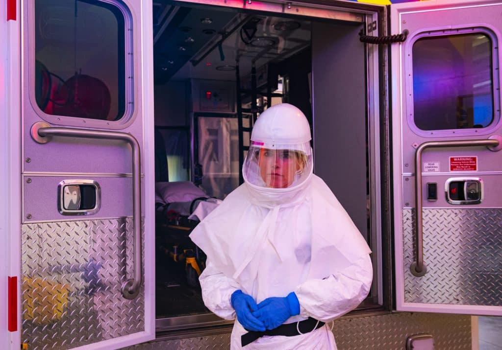 Aspen Ambulance District paramidic Lisa Hicks wears a powered air purifying respirator and a Tyvek suit next to an ambulance in the ambulance bay on Friday, April 3, 2020. The PAPR is now used for transferring patients from Aspen Valley Hospital to a higher level of care, like Denver or Glenwood Springs. Hicks is one of about eight full-time staff members at the ambulance district that has a critical care certificate. “I feel like I am one of the few people that can help people here,” Hicks said. “But I have to stay healthy to do so.” She said that when she first put the PAPR on, her children cried because they were scared of the virus and her intense suit. She explained to them that it would keep her safe and healthy. 