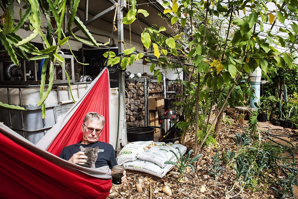Jerome Osentowski, 78, holds one of his two cats in his hammock while enjoying his daily smoothie in a greenhouse at Central Rocky Mountain Permaculture Institute in Basalt on Wednesday, April 1, 2020. (Kelsey Brunner/The Aspen Times)