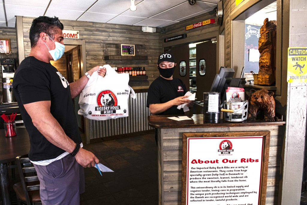 Hickory House’s Henry Pineda gives a take-out customer his receipt in Aspen on Wednesday, April 22, 2020. (Kelsey Brunner/The Aspen Times)