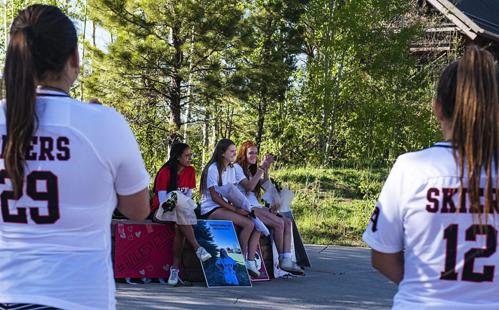 Teammates of the Aspen’s girls soccer seniors Karen Galvan, left, Payton Curly and Maeve McGuire cheer for them during a drive-by parade with signs and honking to honor them during a rose ceremony in the Aspen Recreation Center parking lot on Monday, May 18, 2020. (Kelsey Brunner/The Aspen Times)