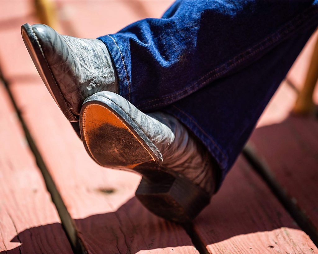 Looking every part the cowboy, Rodeo Hall of Fame inductee George Culbreath crosses his boots as he reclines on the deck of his ranch in Heeney on Saturday, May 30.