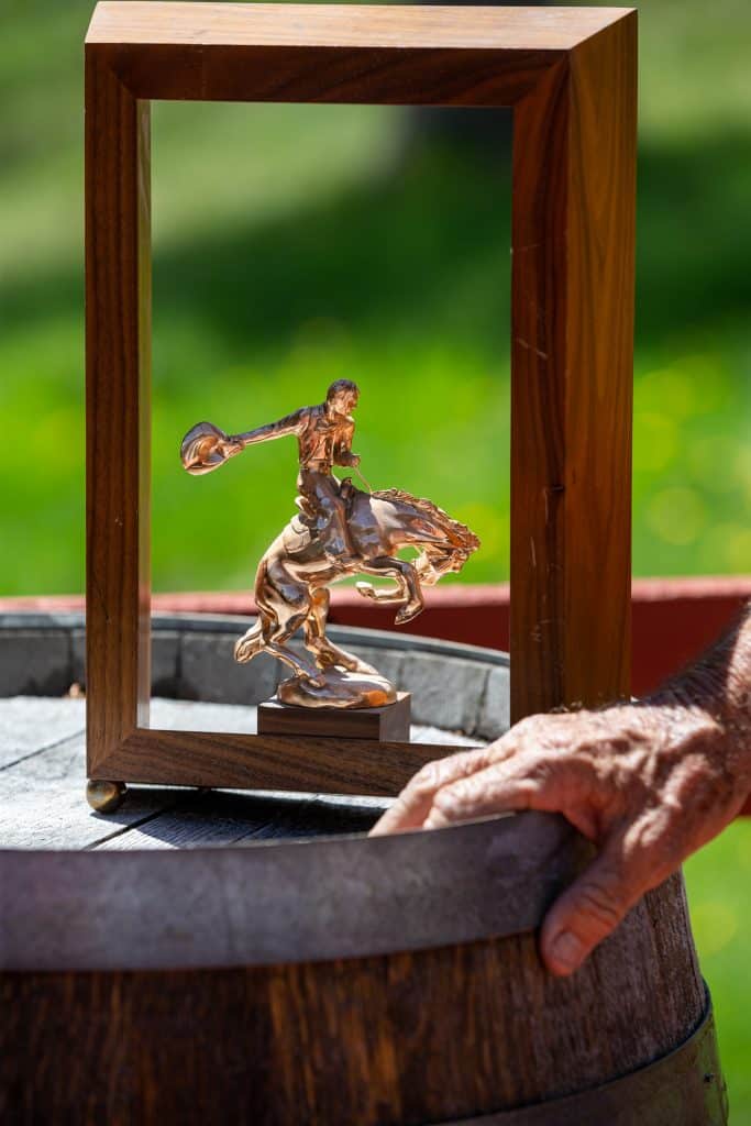 Photographed on his Heeney ranch on May 30, George Culbreath rests his hand near a championship trophy