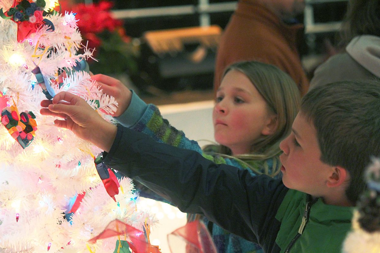 Jacob Cox, front, and Reagan Thompson take a closer look Friday at ornaments on a tree in the New Ute Events Center.