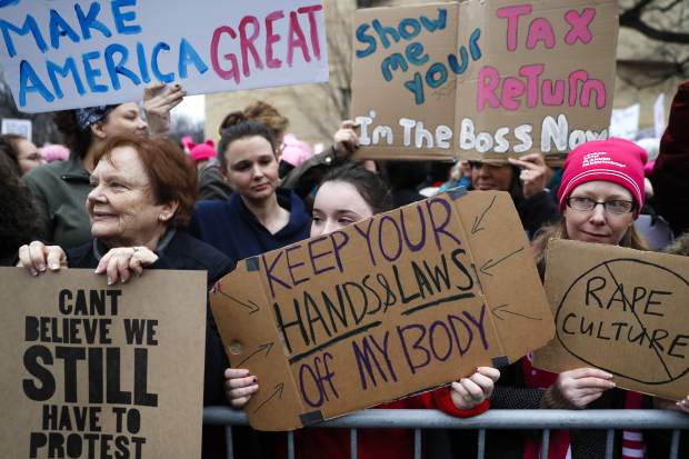 Lily Donahue of Wappingers Falls, N.Y., center, holds a sign along the barricades at the Women's March on Washington during the first full day of Donald Trump's presidency, Saturday, Jan. 21, 2017 in Washington.