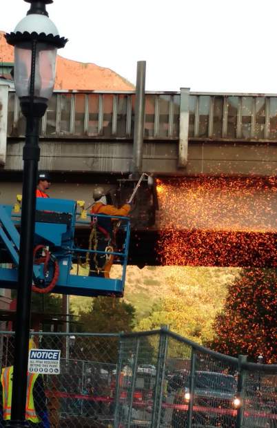 A worker cuts away metal from the Grand Avenue bridge structure that's being demolished.