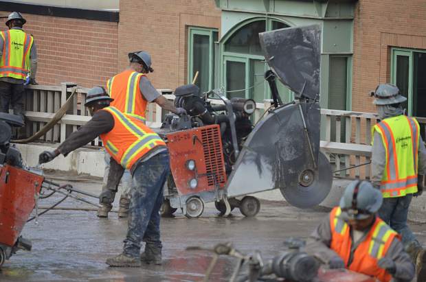 Crews on top of the old Grand Avenue bridge use heavy machinery to slice up sections of the bridge, prepping it to be ripped up and hauled off.