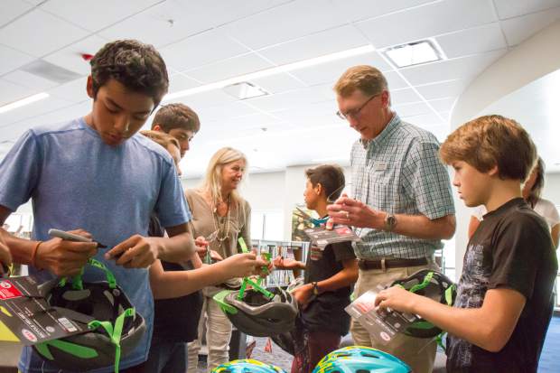 Alpine Bank employee Kent Wilson helps students cut off the tags of their new bike helmets.