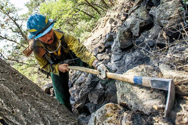 Oregon firefighter Markus Idroga puts out hot spots above the Wilds neighborhood in Basalt from the Lake Christine Fire on Sunday afternoon.