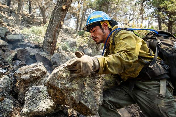 Oregon firefighter Ismael Corona moves rocks and puts out hot spots above the Wilds neighborhood in Basalt from the Lake Christine Fire on Sunday afternoon.