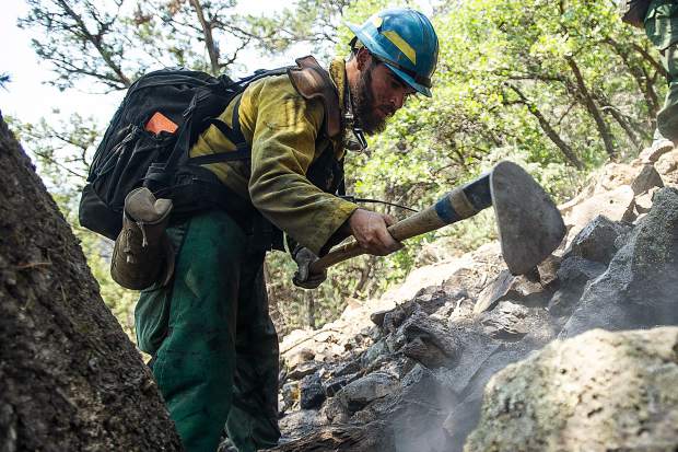 Oregon firefighter Markus Idroga puts out hot spots above the Wilds neighborhood in Basalt from the Lake Christine Fire on Sunday afternoon.