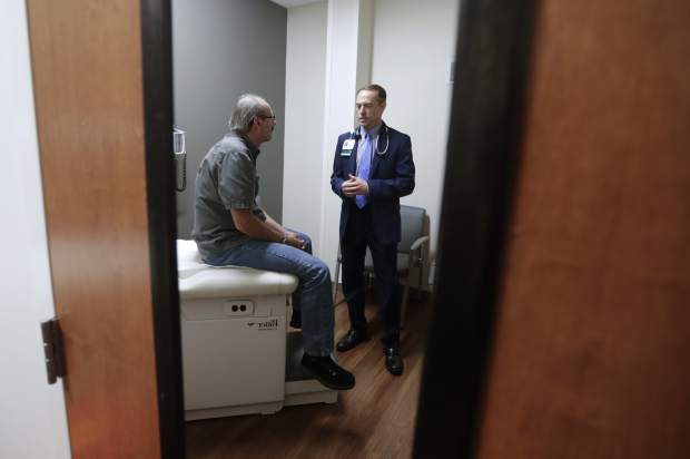Dr. John Lynch meets with patient Jeff Thieke during his visit to the Fiat Chrysler Automotive Clinic in Anderson, Ind., Tuesday, Sept. 4, 2018. Fiat Chrysler is offering free care for its employees and their families, about 22,000 people, through a clinic the carmaker opened this summer near one of five factories it operates in the area. (AP Photo/Michael Conroy)