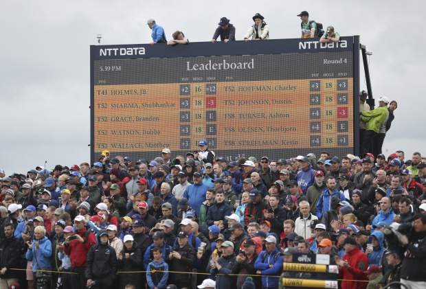 Spectators clamber on to and on top of a scoreboard as they vie to get a glimpse of Ireland's Shane Lowry and England's Tommy Fleetwood as they play during the final round of the British Open Golf Championships at Royal Portrush in Northern Ireland, Sunday, July 21, 2019.(AP Photo/Peter Morrison)