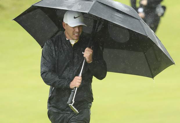Brooks Koepka of the United States walks onto the 10th green as he shelters from the heavy rain under an umbrella during the final round of the British Open Golf Championships at Royal Portrush in Northern Ireland, Sunday, July 21, 2019.(AP Photo/Jon Super)