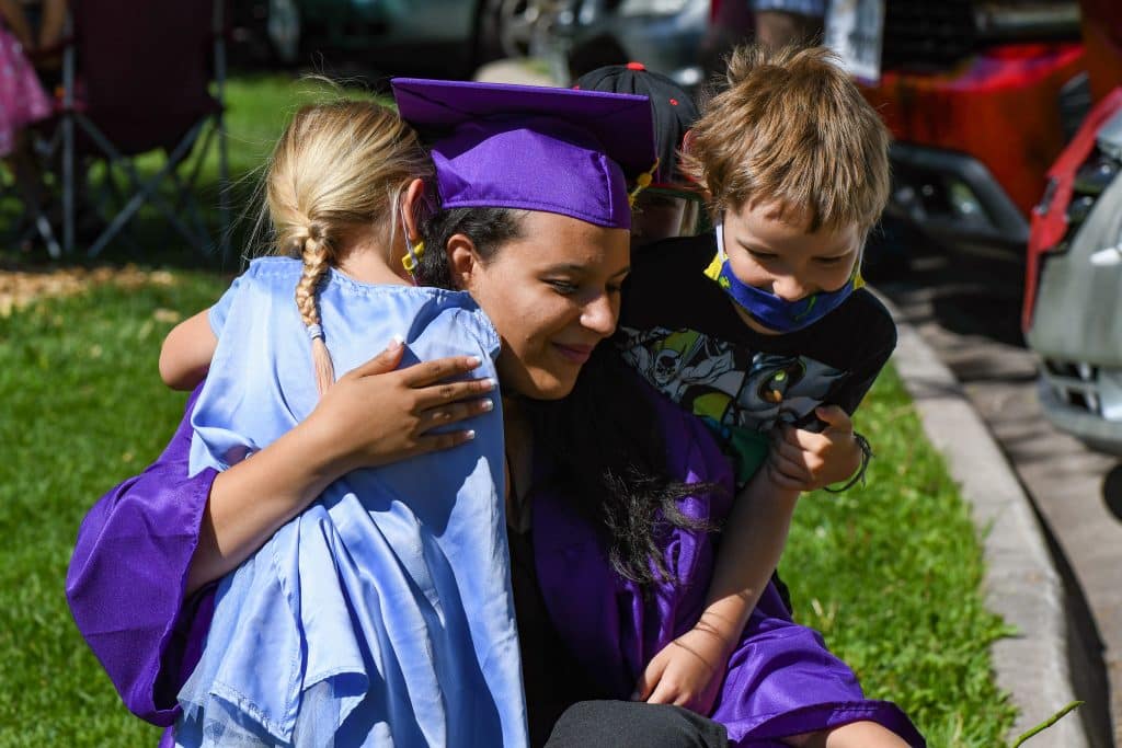 A Yampah Mountain High School class of 2020 graduate is embraced by family before the start of the drive-in ceremony on Friday morning.