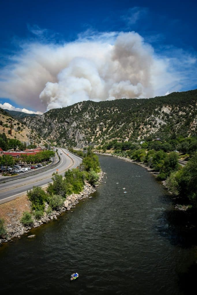 People float down the Colorado River as smoke billows from the Grizzly Creek Fire in Glenwood Canyon on Monday afternoon.