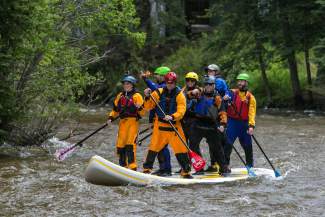 A stand-up paddle party of seven make their way into Vail Villiage while cruising Gore creek during the GoPro Mountain Games on Saturday.