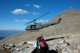 Carl Gray, at the controls of this Huey, drops a search and rescue team on Mount of the Holy Cross. After years with HAATS and two tours in Vietnam, Gray retired this week.