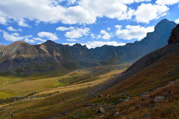 Traversing a grassy slope, while simultaneously descending into the magnificent Wetterhorn Basin. Wetterhorn Peak (on the right) is a 14,000 foot mountain in the San Juan range.