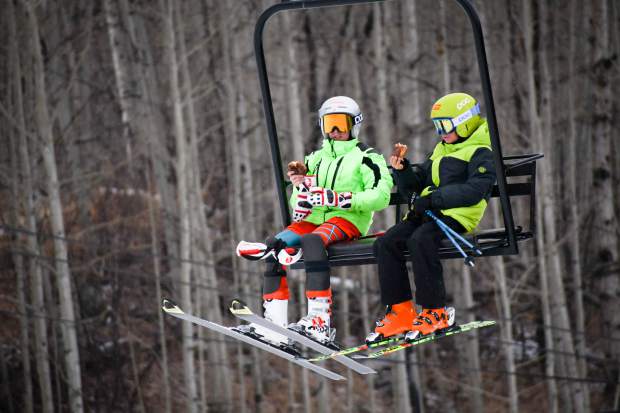 A couple of ski friends take the lift up to the Midway run with free doughnuts in hand during the opening day at Sunlight Mountain.