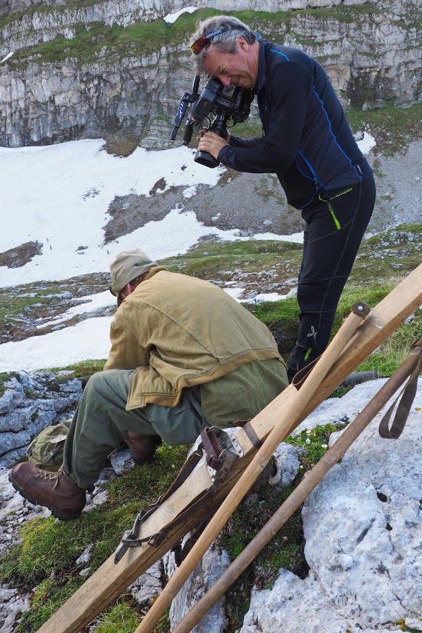 A cameraman gets footage of Anthony lacing up the vintage leather ski boots before the film the reenactment of the ski race on Mt. Mangart on June 3, 1945. 