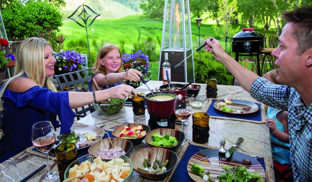 Fondue at Home offers the perfect summer at-home catered meal, with a melted cheese pot along with a hot pot of beef broth that stays warm as the even outside cools off along with plenty of meat, bread and vegetable options to dip in the fondue.