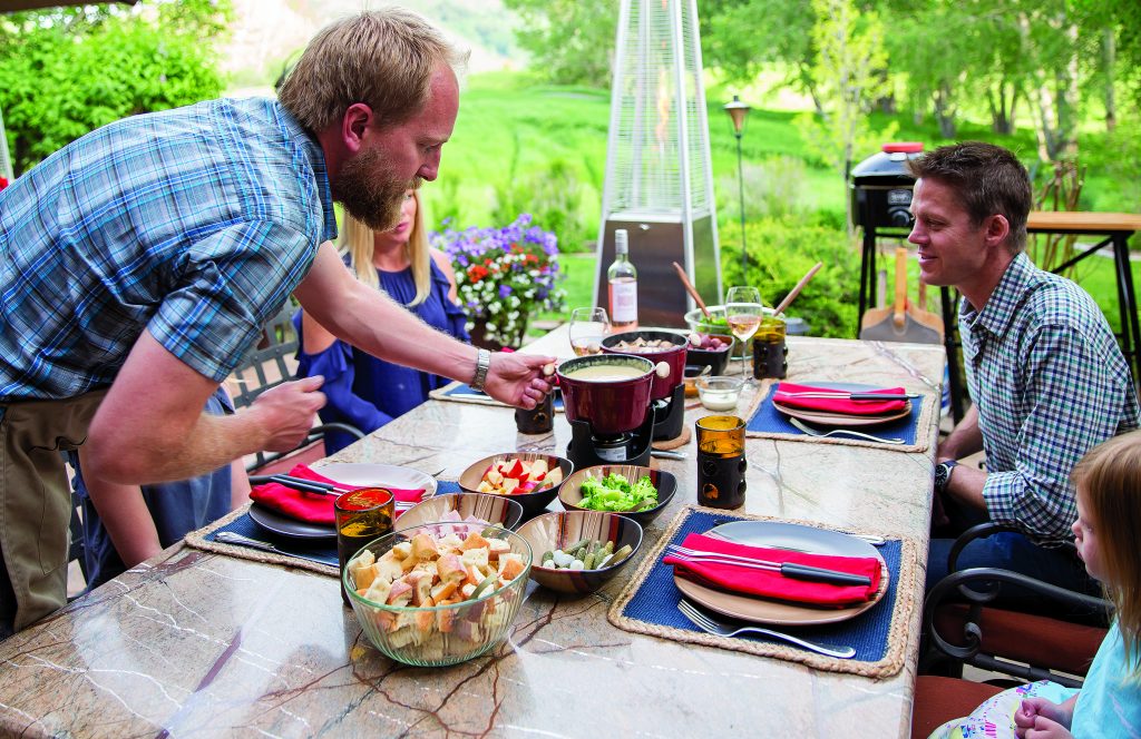 Derek George, owner of Fondue at Home provides the perfect summer outdoor dining experience a fully catered fondue meal at home. The meal includes a melted cheese pot and a hot pot of beef broth that stays warm as the evening cools down along with plenty of meat, bread and vegetable options to dip in the fondue and a fresh salad and a dessert fondue pot.