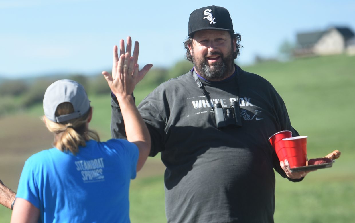Tripp Hartigan hands out beer, doughnuts and high fives along County Road 129 on Sunday during the Steamboat Marathon.