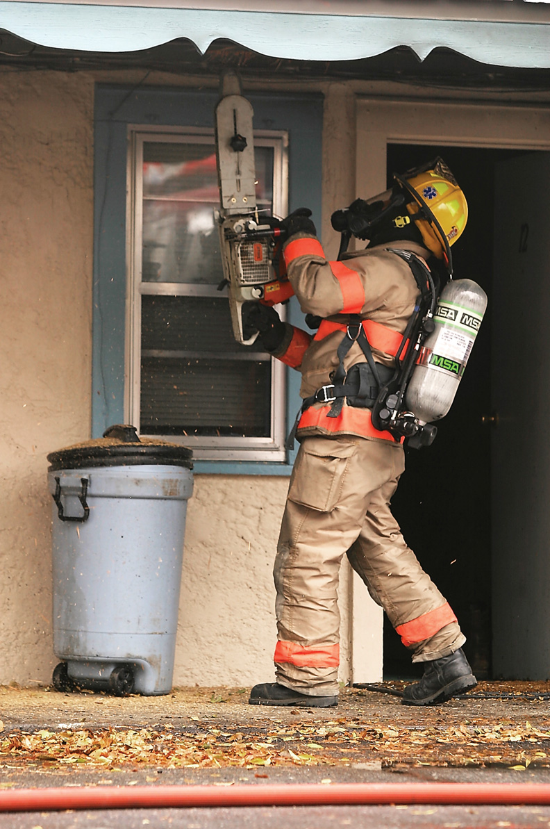 A Craig Fire/Rescue official uses a chainsaw to cut a hole in the Craig Motel roof so others can spray flame retardant inside.
