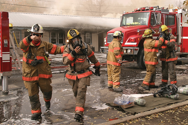 A Craig Fire/Rescue firefighter helps a colleague get checked out by medics after his tank alarm sounded, alerting him of low oxygen levels.
