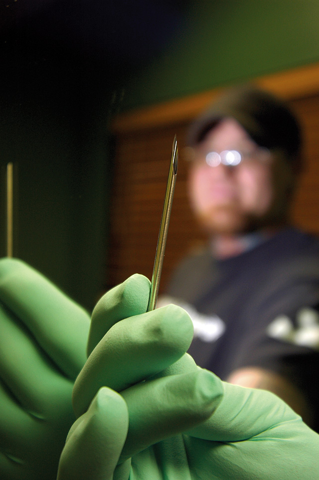 Piercer Jasen Phelps holds a needle used for body piercing.