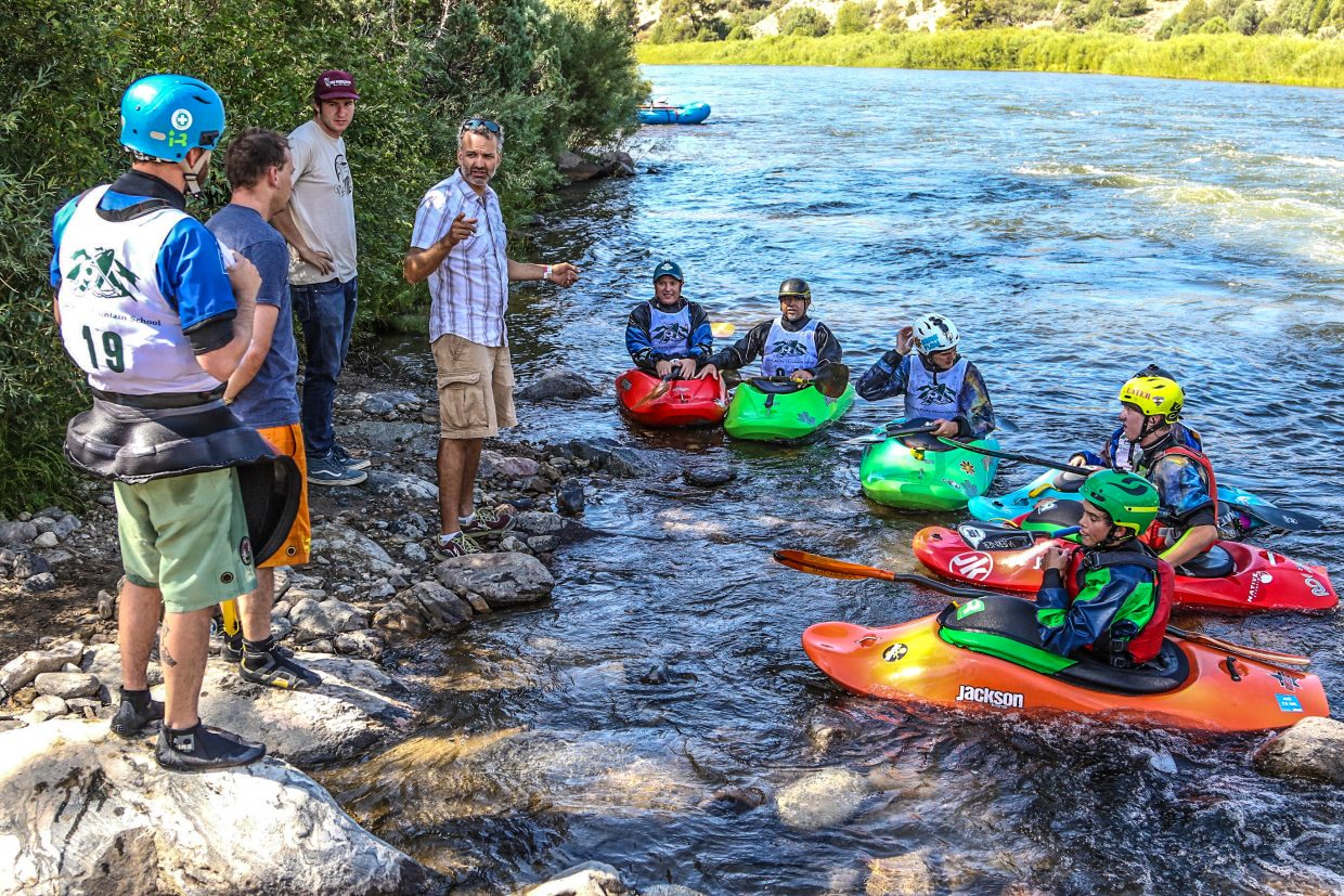 A group of kitted out kayakers rest along the banks of the Colorado listening to instructions.