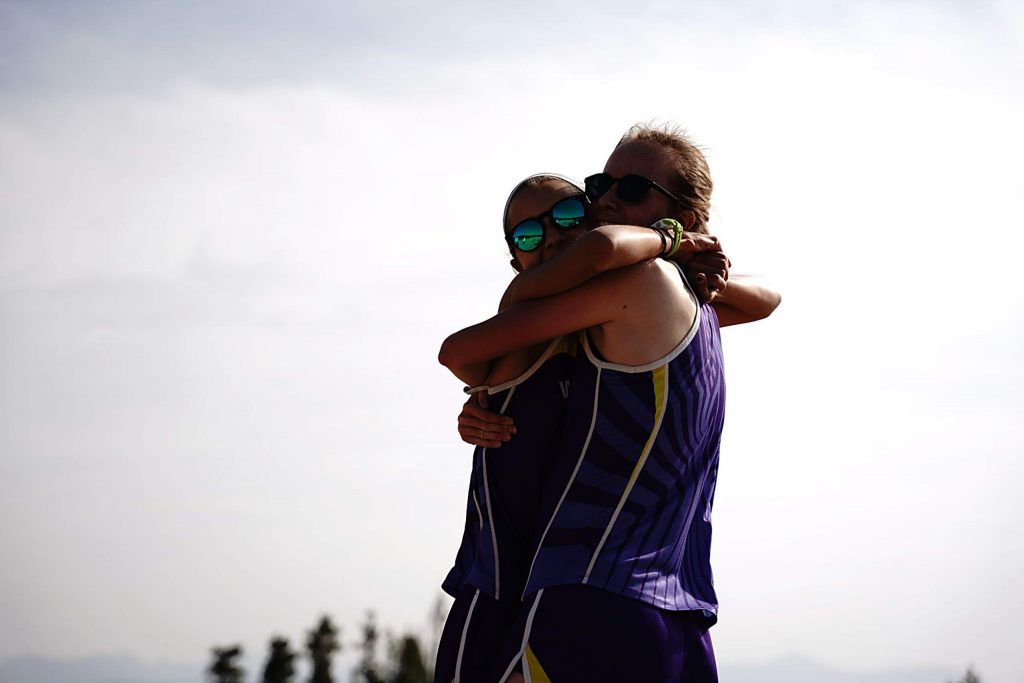 West Grand's Allura Luna and Samantha Westfahl hug after finishing the 3.1 mile course Saturday at Snow Mountain Ranch. Luna recorded the top finish for the Mustangs in the race by taking second.